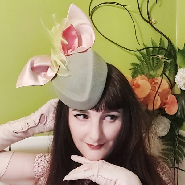 Chapeau de cocktail rétro en feutre gris. Style vintage avec grand nœud corail et soie et plumes vertes. Oh... Really? par Sandra Lacroix, chapelière, Bruxelles.